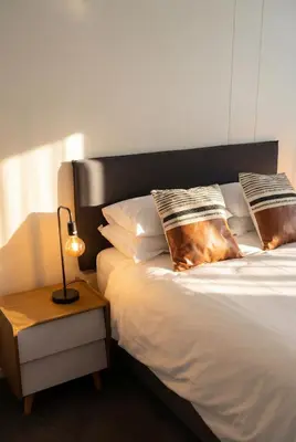 a bed with pillows and a lamp on a table at Tyger Lake Luxury Loft in Cape Town