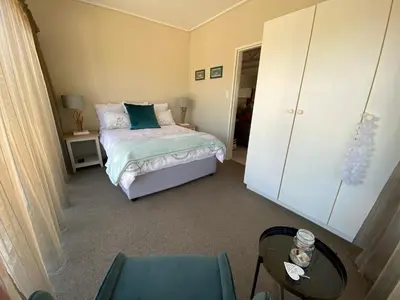 a small bedroom with a bed and a table at Onrus Beach House in Hermanus