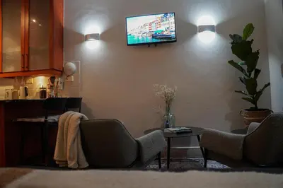 a living room with two chairs and a tv on the wall at 7 on Huis Piron in Stellenbosch