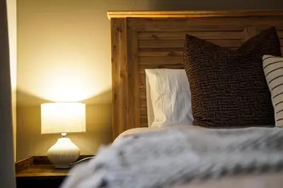 a bed with a wooden headboard and a lamp on a table at 7 on Huis Piron in Stellenbosch