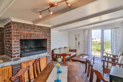 a living room with a brick fireplace and a table at Penguin's Nest in Bettyʼs Bay