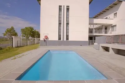 a large blue swimming pool in front of a building at Sunny Escapes Rentals in Cape Town