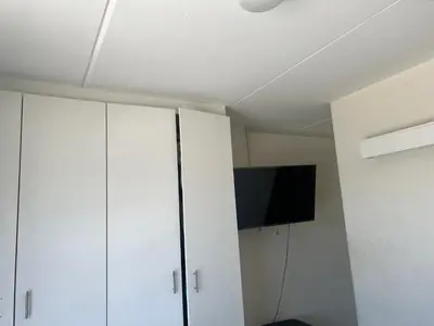 a room with white cabinets and a flat screen tv at Sunny Escapes Rentals in Cape Town