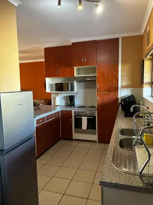 a kitchen with wooden cabinets and a stainless steel refrigerator at Gordon's Bay Townhouse in Gordonʼs Bay