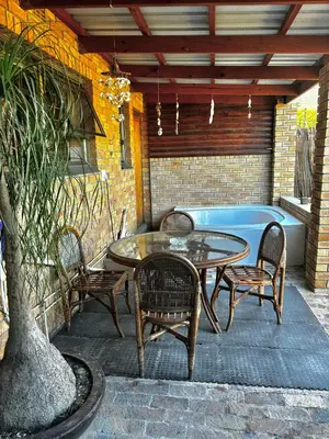 a patio with a table and chairs and a tub at Gordon's Bay Townhouse in Gordonʼs Bay