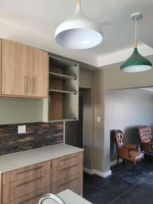a kitchen with wooden cabinets and two chairs at Nana Guest House in Cape Town