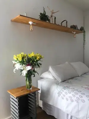 a vase of flowers on a table next to a bed at Serene Studio in Cape Town