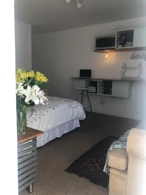 a bedroom with a bed and a table with flowers on it at Serene Studio in Cape Town