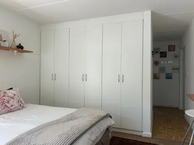 a bedroom with white cabinets and a bed at Serene Studio in Cape Town