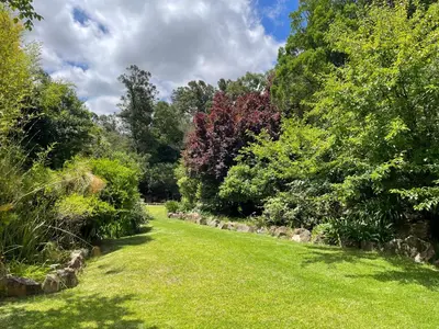 a garden with green grass and trees in the background at Basco River Lodge Holiday Villa in Grabouw