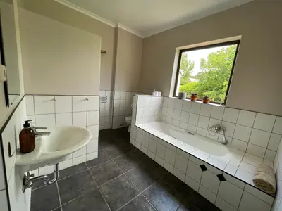 a bathroom with a tub and a sink and a window at Basco River Lodge Holiday Villa in Grabouw