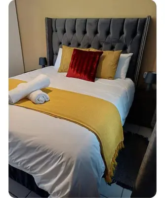 a large bed with a red pillow and yellow blanket at Oakway Guest Suite in Cape Town