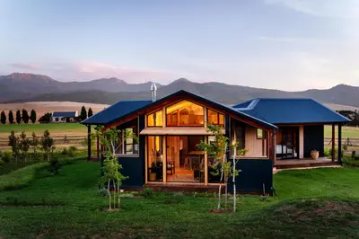 a house in a field with mountains in the background at Natimby Lodge in Botrivier