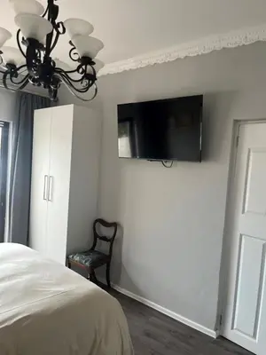 a bedroom with a bed and a tv on the wall at Annebella's in Gordonʼs Bay