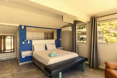 a bedroom with a large bed with a blue wall at Bikini Beach Townhouse in Gordonʼs Bay