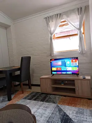 a living room with a tv and a table and a window at The Berna in Cape Town