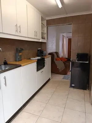 a kitchen with white cabinets and a black refrigerator at The Berna in Cape Town