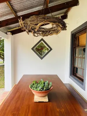 a vase sitting on a wooden table with a plant at 9de Laan Kleinmond in Kleinmond