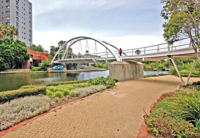 a bridge over a river with people walking on it at Waters Edge Uno in Cape Town