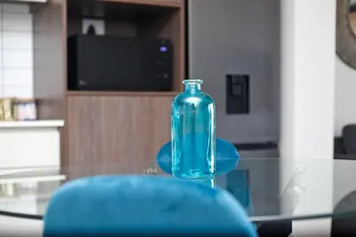 a glass bottle sitting on a glass table with a blue chair at Waters Edge Uno in Cape Town