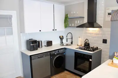 a kitchen with a washing machine and a sink at Yellow Couch Studio Apartment 1 KingBed in Cape Town