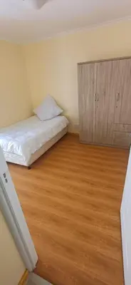 a bedroom with a bed and a wooden floor at Cosy Cove in Grassy Park