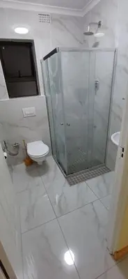a white bathroom with a shower and a toilet at Cosy Cove in Grassy Park