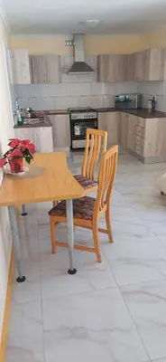 a kitchen with a wooden table and a table and chairs at Cosy Cove in Grassy Park