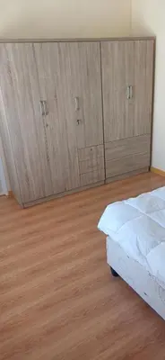 a bedroom with wooden cabinets and a bed at Cosy Cove in Grassy Park