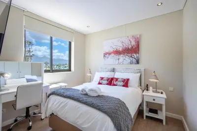 a white bedroom with a bed and a desk and a desk at Atlantica202 in Strand