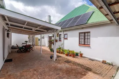 a white house with a green roof with a patio at 162 on 6th in Hermanus