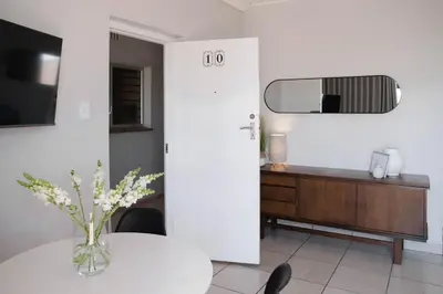 a white room with a table and a mirror at Seabreeze at the Beach in Strand