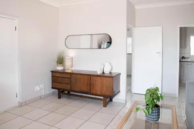 a living room with a wooden dresser and a mirror at Seabreeze at the Beach in Strand