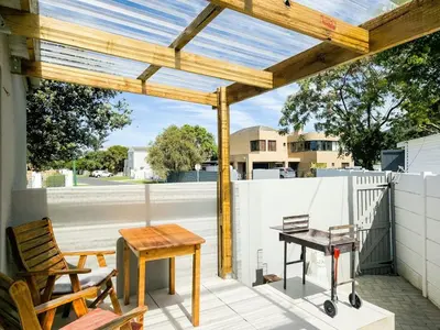 a patio with a wooden pergola and a table at Seewind in Hermanus