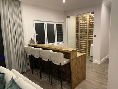 a kitchen with a bar with white stools at Whale Coast Luxury in Bettyʼs Bay