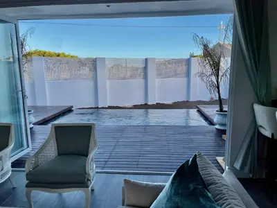 a living room with a couch and a chair on a patio at Whale Coast Luxury in Bettyʼs Bay