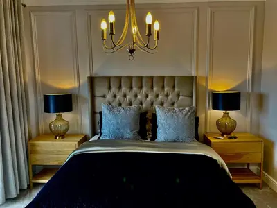 a bedroom with a bed with two lamps and a chandelier at Whale Coast Luxury in Bettyʼs Bay