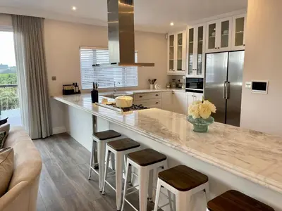 a kitchen with a large counter with stools at Whale Coast Luxury in Bettyʼs Bay