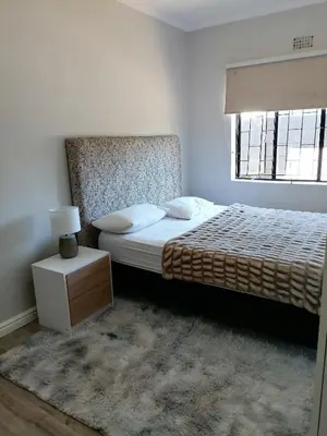 a white bedroom with a bed and a window at Urban Sleek Black Haven in Cape Town