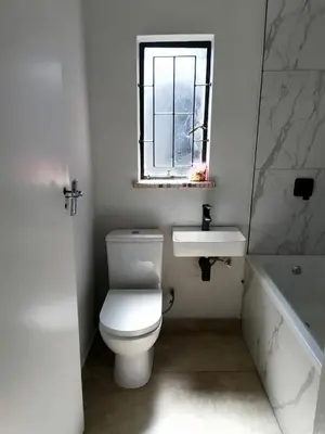 a bathroom with a toilet and a sink and a window at Urban Sleek Black Haven in Cape Town