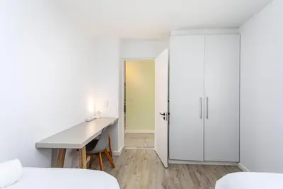 a white bedroom with a desk and a door at Sea Spray B303 by CTHA in Cape Town