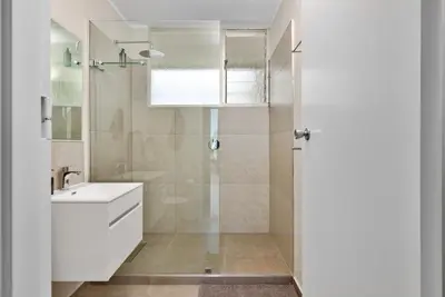 a white bathroom with a shower and a sink at ZenDen Destinations' Seaside Sanctuary Suite in Strand