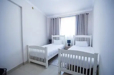 two white cribs in a white room with a window at Cape Dreamland in Cape Town