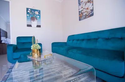 a living room with a blue couch and a glass table at Cape Dreamland in Cape Town