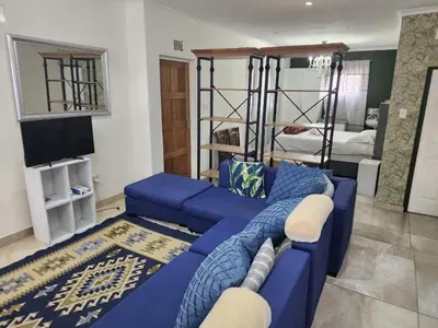 a living room with a blue couch and bunk beds at Tia Maria bachelor apartment in Cape Town