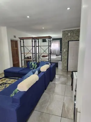 a living room with a blue couch and a bed at Tia Maria bachelor apartment in Cape Town