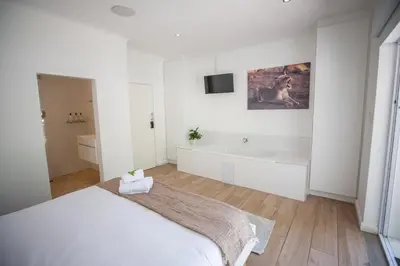 a white bedroom with a bed and a bath tub at theLAB Luxury Backpackers in Franschhoek