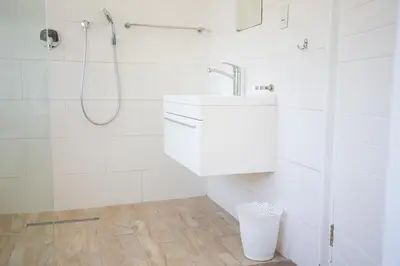 a white bathroom with a shower and a sink at theLAB Luxury Backpackers in Franschhoek