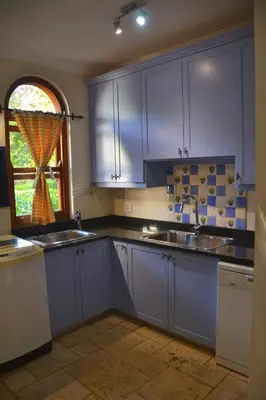 a kitchen with blue cabinets and a sink and a window at Lovely Family Home in the Winelands in Cape Town