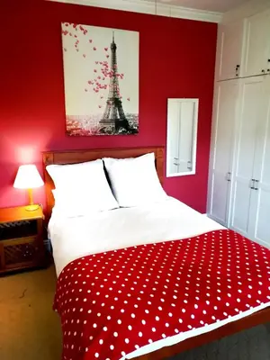 a bedroom with a bed with a red wall at Lovely Family Home in the Winelands in Cape Town
